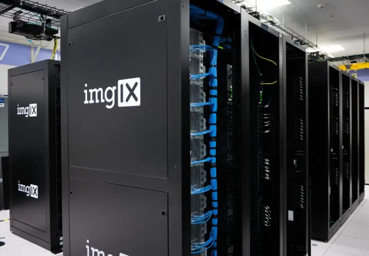 Des racks de serveurs noirs, dont un avec le logo "imgIX", remplis de câbles bleus et jaunes. C'est un peu ça, un serveur : le cœur de l'internet.
