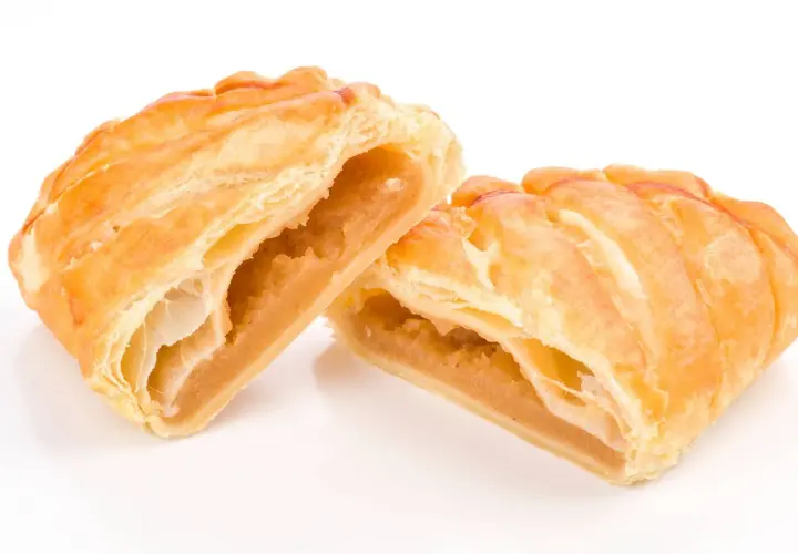 Pastelitos dorados y hojaldrados, cortados por la mitad, revelan un relleno dulce de ingredientes cabello de angel.