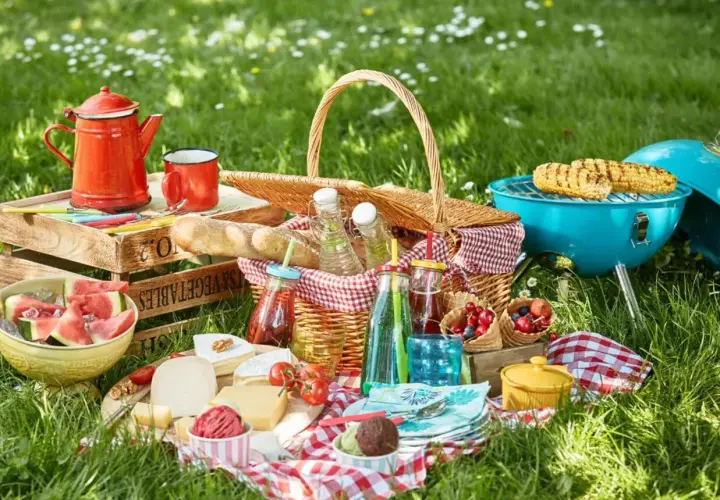 Idealne jedzenie na piknik: kosz pełen smakołyków, grillowana kukurydza, sery, owoce i napoje.