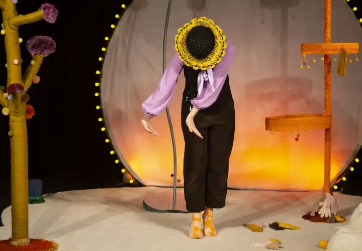 En docka med solros-huvud på scenen, en del av dockteater Stockholm.