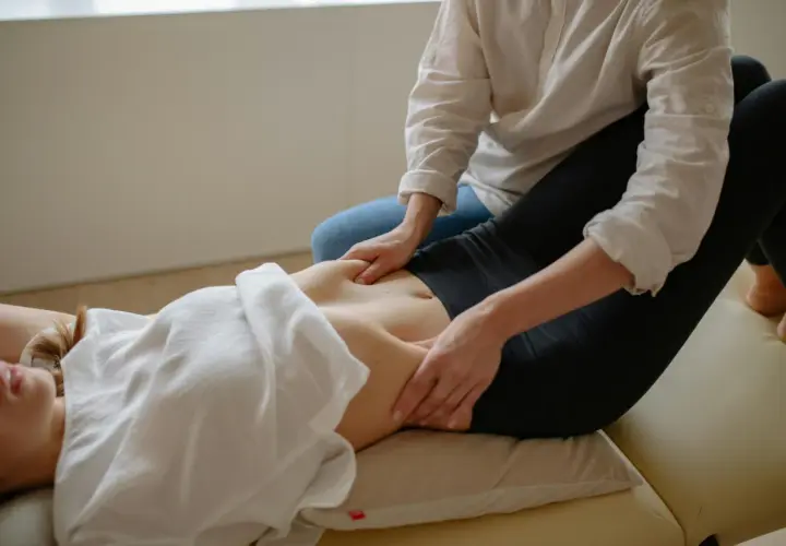 Fizjoterapeuta masuje brzuch, co może pomóc zrozumieć, od czego może boleć przepona.