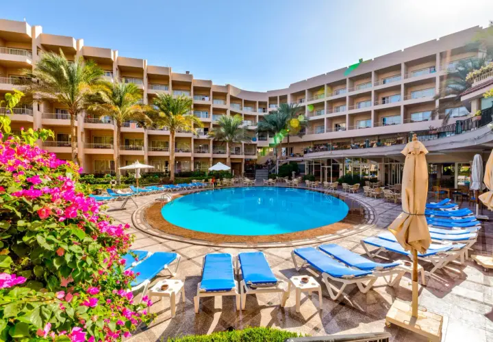 Basen hotelowy Beau Rivage z leżakami i palmami, otoczony budynkami hotelowymi.