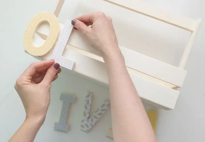 Manos decorando letras para manualidades de comunión, creando un detalle personal para un día especial.
