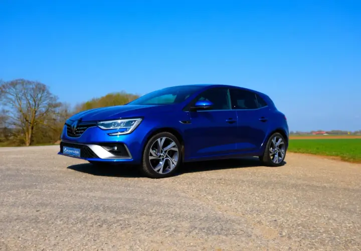 Blauer Renault Mégane 4 RS steht auf einem Feldweg vor grünen Feldern und Bäumen.
