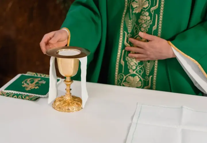 Kapłan w zielonej szacie przygotowuje kielich podczas mszy żałobnej.