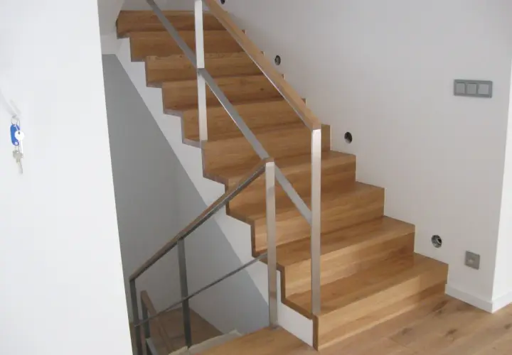 Nowe schody dywanowe na beton, z drewnianymi stopniami i metalową balustradą, tworzą eleganckie i nowoczesne wnętrze.