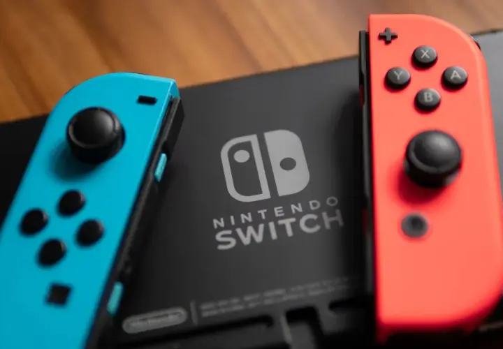 Dwa kontrolery Joy-Con, niebieski i czerwony, leżą obok konsoli Nintendo Switch. Idealne do odkrywania najlepszych gier na Nintendo Switch.