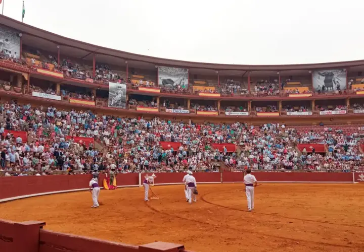 Toros en la grada seis. Multitud expectante en la plaza de toros, con toreros preparándose en la arena.