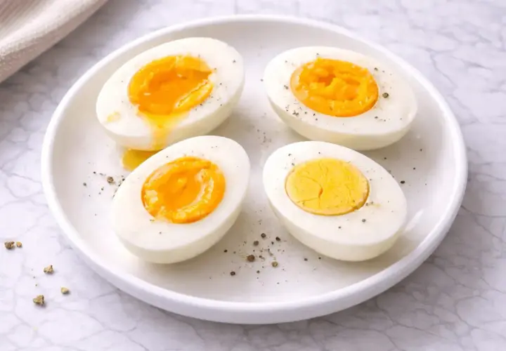 Quatre moitiés d'œufs durs sur une assiette blanche, certains avec un jaune coulant. Le temps d'un œuf parfait.