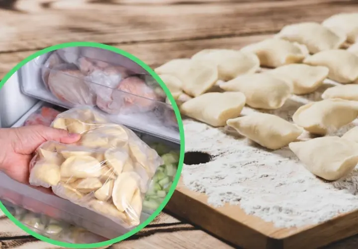 Ręka wkłada do zamrażarki worek z surowymi pierogami, obok leżą uformowane pierogi na desce.