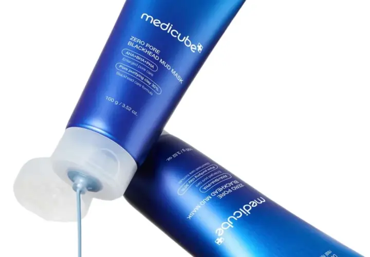 Två blå tuber med Medicube Zero Pore Blackhead Mud Mask. En tub har en öppen kork där masken droppar ut, en lösning för oljig hy orsak.