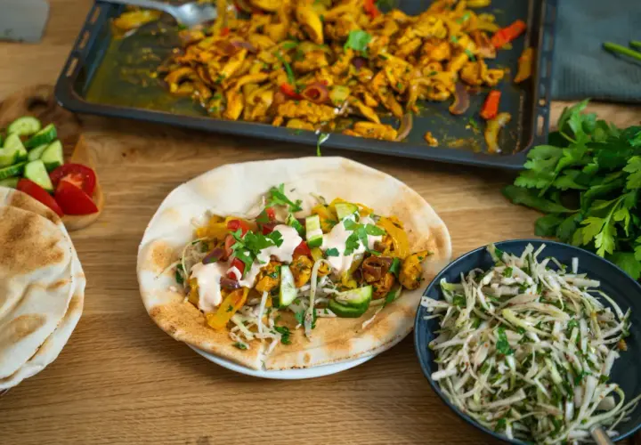 En läcker kyckling shawarma fylld med grönsaker och sås, serverad med pitabröd och en fräsch sallad.