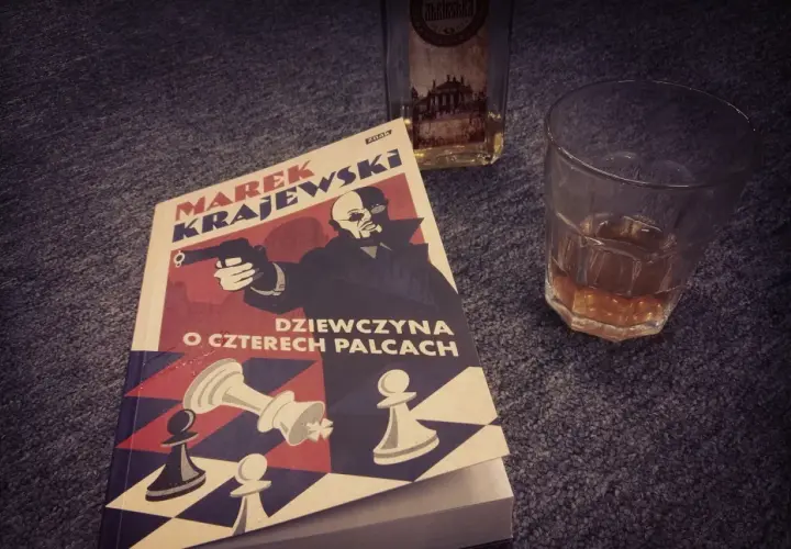 Książka "Dziewczyna o czterech palcach" Marka Krajewskiego, idealna na wieczór z whisky. Kolejność czytania jego powieści jest ważna dla pełnego odbioru.