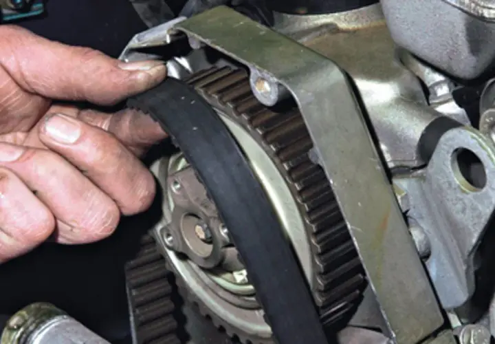 Dłoń mechanika sprawdza stan paska rozrządu, kluczowego elementu silnika.