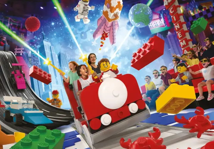 Lego Masters erleben eine Achterbahnfahrt voller Action und Spaß, mit Raketen, Rennwagen und einem Kino im Hintergrund.