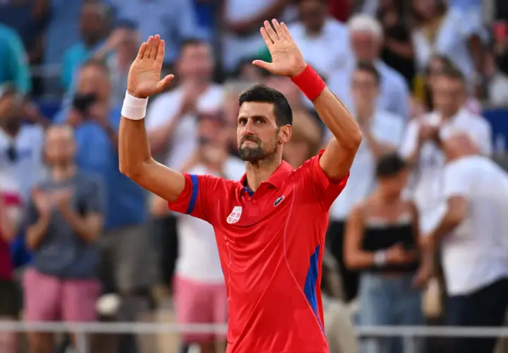 Novak Djoković w czerwonej koszulce z podniesionymi rękami, pozdrawia publiczność po zwycięstwie w turnieju WTA 500.
