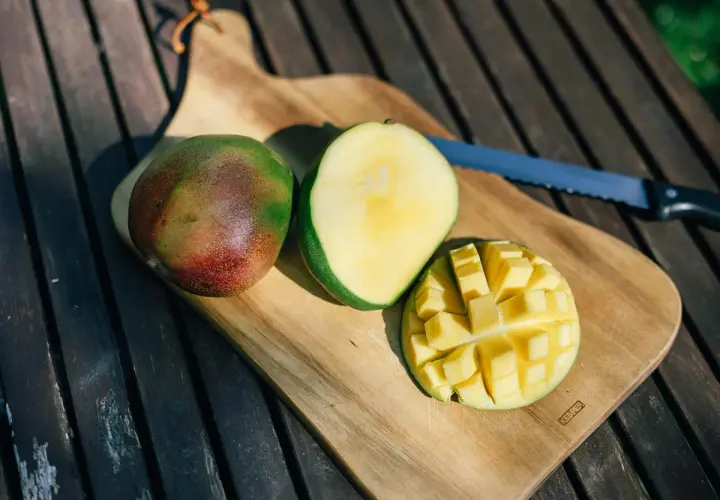 Süße, saftige Mangostücke auf einem Holztisch. Die Frage "ist mango gesund" wird durch diese leckere Frucht beantwortet.
