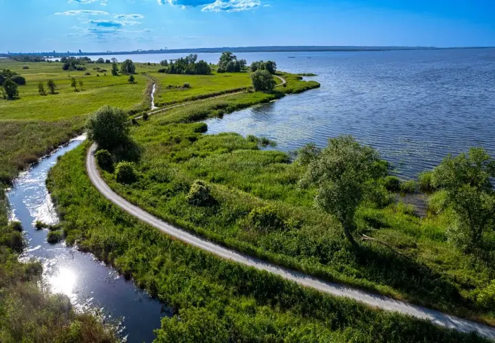 Malownicze trasy rowerowe Szczecin wiodące wzdłuż rzeki i jeziora, otoczone bujną zielenią.
