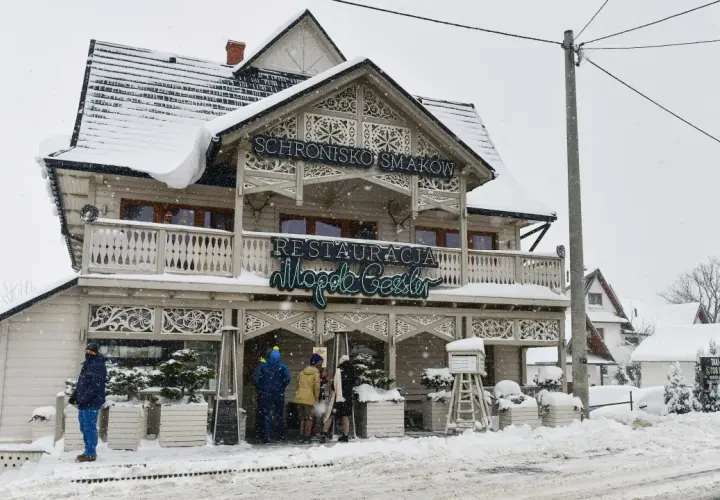 Drewniana restauracja "Schronisko Smaków" w Bukowinie Tatrzańskiej, pokryta śniegiem, z neonem "Restauracja".