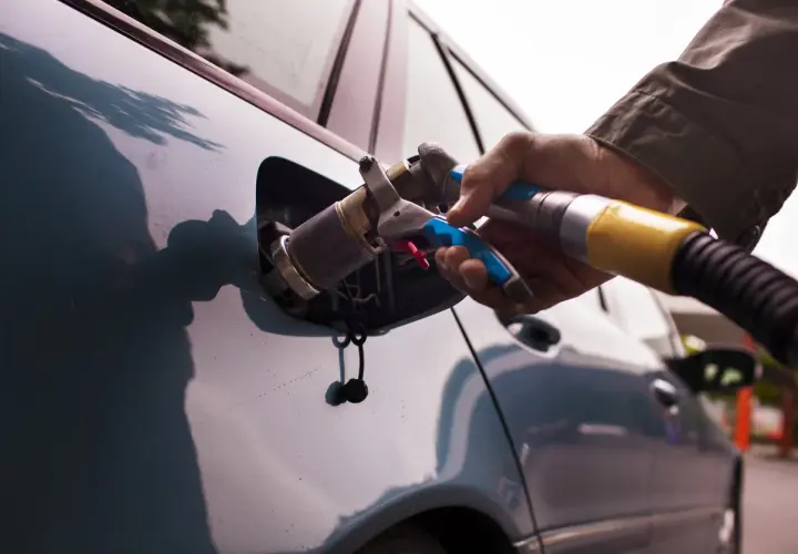 Rifornimento GPL. Se la bombola gpl scaduta posso circolare a benzina? La mano inserisce la pistola di rifornimento nel serbatoio dell'auto.