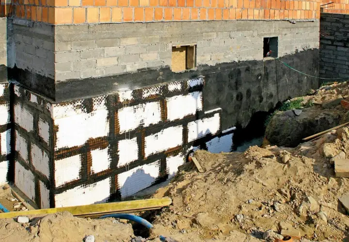 Nowe ściany w piwnicy z izolacją i siatką. Budowa fundamentów domu.