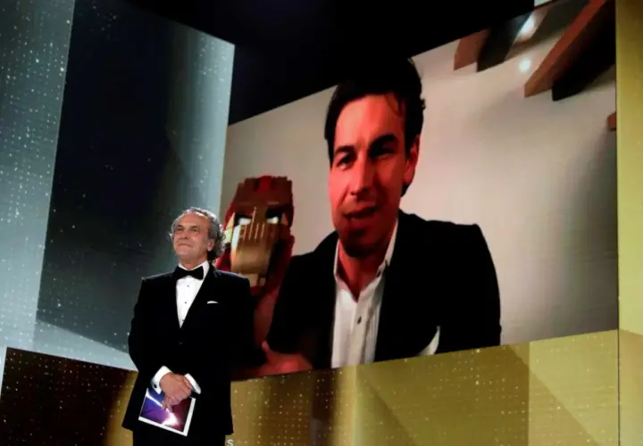 Presentador en los Goya con Mario Casas en pantalla, quien sostiene un premio.