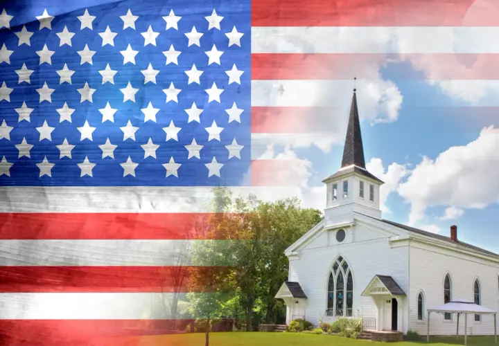 Amerikanische Flagge über einer weißen Kirche, die die Präsenz von Katholiken in den USA symbolisiert.