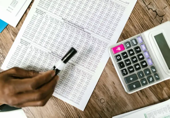 Tabela z danymi finansowymi, kalkulator i ręka analizująca układ rodzajowy kosztów.