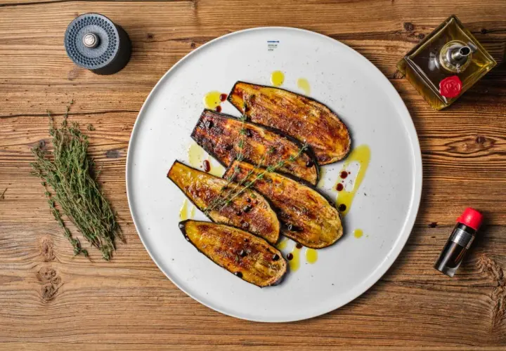 Gegrillte Auberginenscheiben als Antipasti, beträufelt mit Olivenöl und Balsamico, garniert mit Thymian.