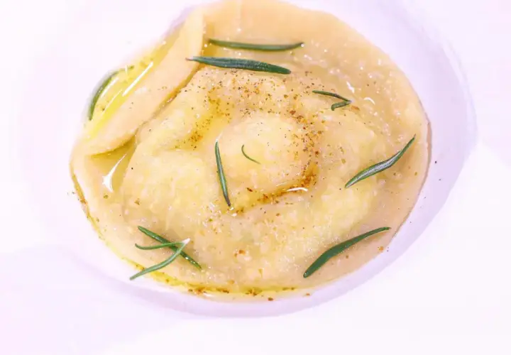 Ravioli z płynnym żółtkiem, ozdobione rozmarynem i przyprawami, danie godne MasterChefa.