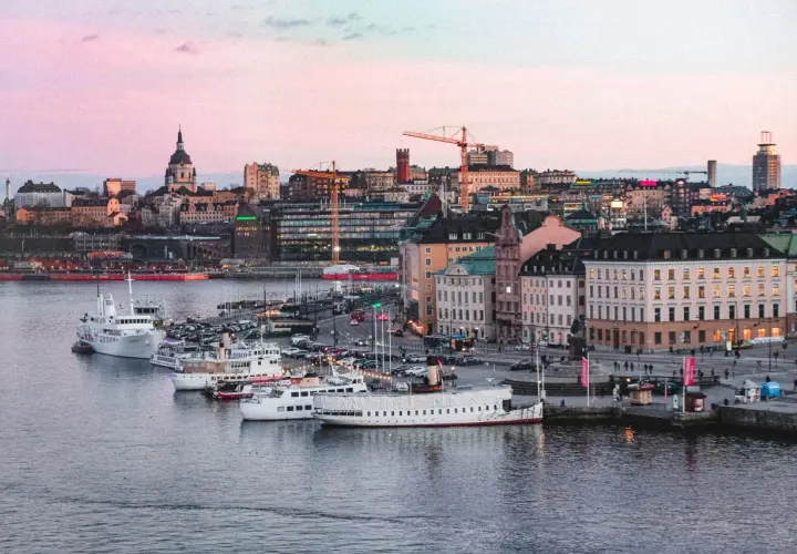 Vackert ljus över vattnet och båtar vid kajen i Stockholm. Staden ser inbjudande ut, redo för äventyr imorgon.