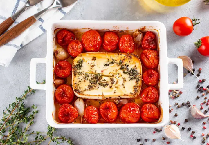 Feta in friggitrice ad aria, circondata da pomodorini arrostiti, aglio e erbe aromatiche. Un piatto semplice e gustoso.