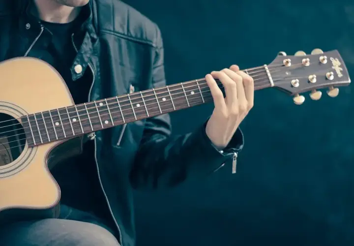 Mężczyzna w skórzanej kurtce gra na gitarze. Palce na gryfie tworzą akord, który brzmi jak początek rockowej ballady. Jaki to akord?