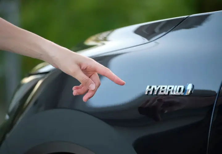 Dito il logo "Hybrid" su una Toyota Yaris. Si pensa al costo del bollo per un'auto ibrida.