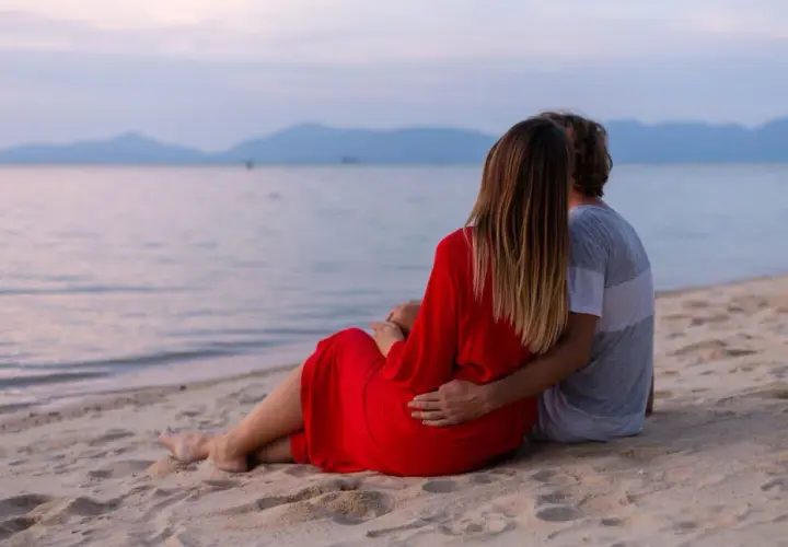 Para dla dwojga siedzi na plaży, patrząc na morze. To fajne miejsce nad morzem dla dwojga, idealne na romantyczny wieczór.