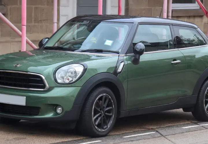 Zielony mini paceman stoi na ulicy, mokry od deszczu.