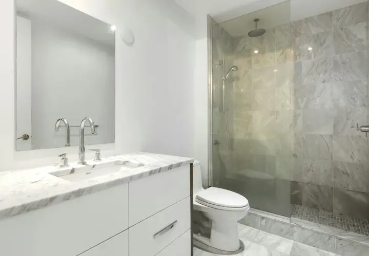 Modernt badrum med marmor, dusch och toalett. Enkel design som visar att det går att renovera badrum billigt med stil.