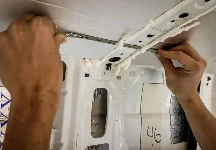 Application de mousse isolante sur la structure intérieure d'un fourgon, étape clé du plan camping-car.