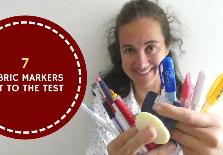 A woman smiles, holding a collection of colorful marking tools for sewing, ready to put them to the test.