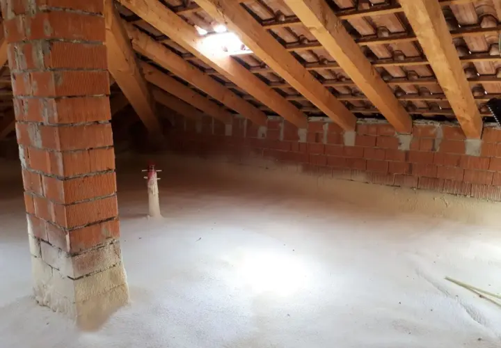 Sottotetto in fase di isolamento con schiuma espansa. Si vede la struttura in legno e mattoni, segno che conviene isolare il sottotetto per un maggiore comfort.