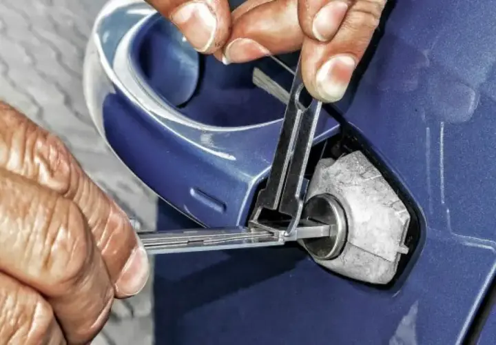 Manos expertas intentan abrir coche sin llave con herramientas especializadas.