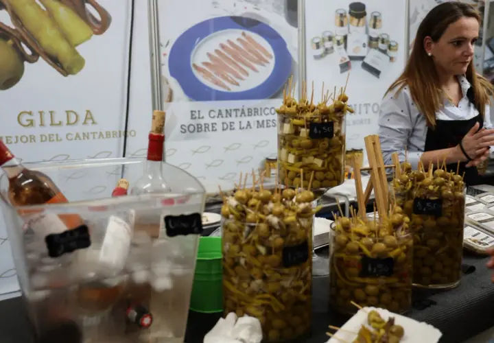 En la feria de la anchoa en Santoña, se exhiben gildas y aceitunas marinadas. Botellas de vino esperan ser servidas.