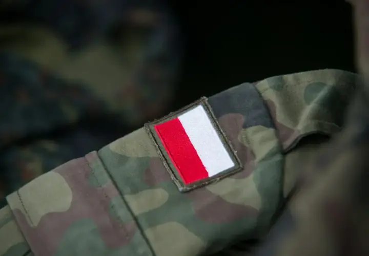 Fragment munduru wojskowego w kamuflażu z naszywką z polską flagą. Różne rodzaje mundurów wojskowych mają swoje unikalne oznaczenia.