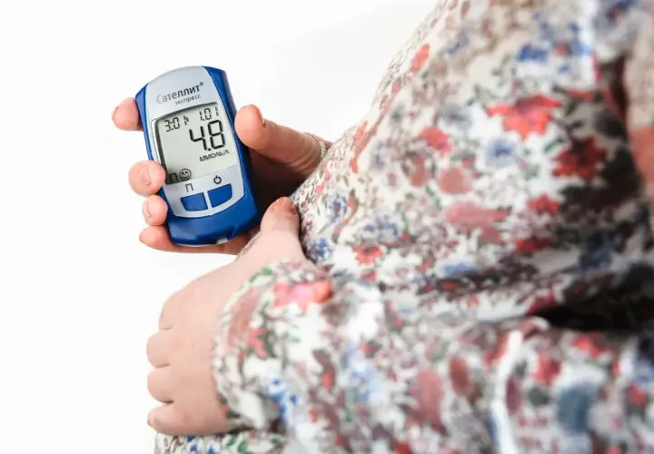 Gravid kvinna kontrollerar sitt blodsocker med en glukosmätare. En viktig del av att hantera graviditetsdiabetes.