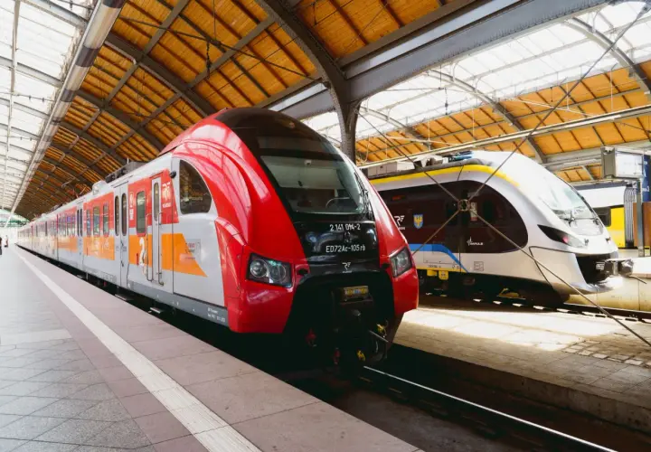Dwa nowoczesne pociągi stojące na peronie. Czerwony pociąg Polregio i biało-niebieski Impuls, gotowe do podróży. Połączenie kolejowe Wrocław.