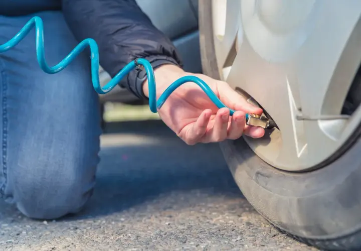 Persona infla ruedas con nitrógeno usando una manguera azul.