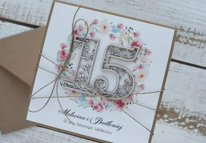 Elegancka kartka z okazji 15 rocznicy ślubu Malwiny i Bartłomieja, ozdobiona kwiatowym wianuszkiem i ażurową cyfrą "15".