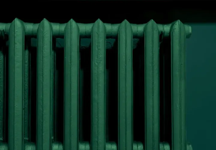 Un termosifone in ghisa, appena verniciato di un verde scuro e profondo, pronto a scaldare l'ambiente.