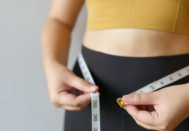 Kobieta mierzy talię centymetrem. Chcesz wiedzieć, jak podkręcić metabolizm po 40.? To pierwszy krok do celu.