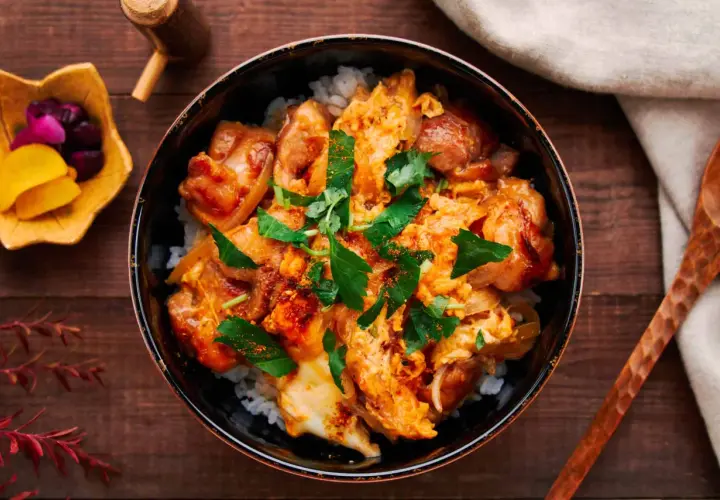 A delicious oyaku donburi recipe, featuring tender chicken and fluffy egg over rice, garnished with fresh parsley.